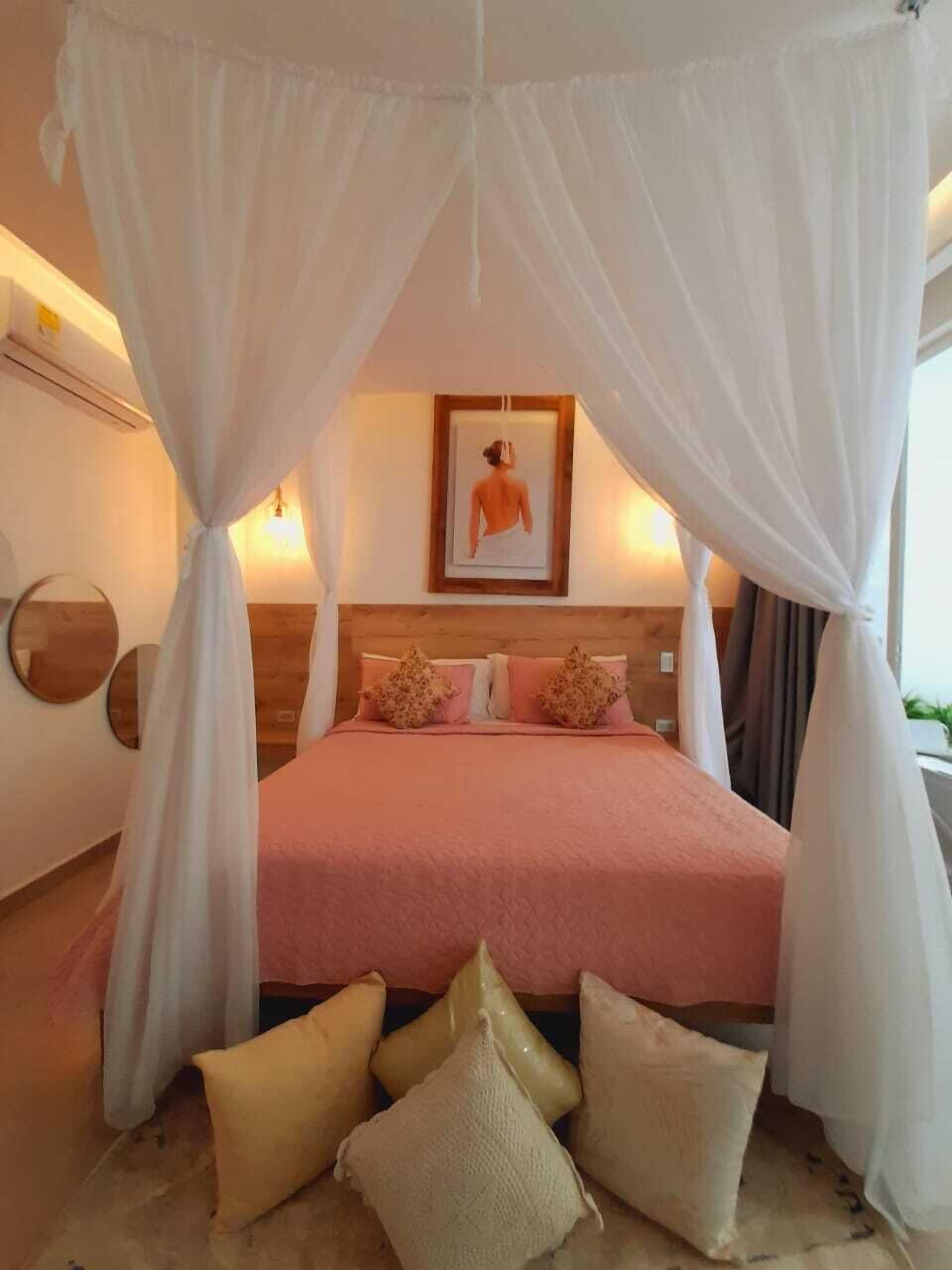 Quarto com cama de dossel, um quadro na parede e mesa de cabeceira.