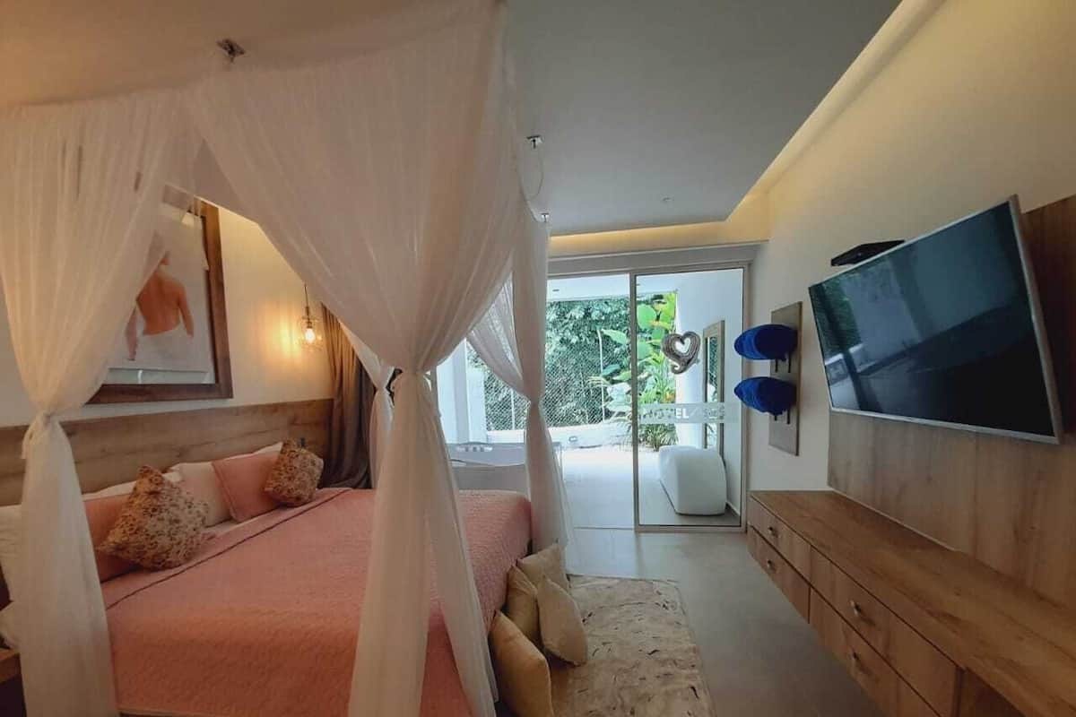 A bedroom with a bed, a TV, and a view of the outdoors.