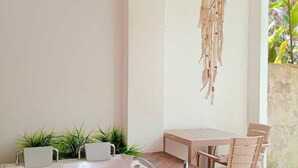 Un baño moderno con una bañera independiente, una mesa con sillas y decoración de macramé colgante.