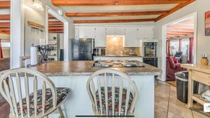 A kitchen with white cabinets, a central island, and wooden beams on the ceiling. - Charming 2-bedroom house in Ruidoso with AC, WiFI, pellet stove, hot tub (Ruidoso)