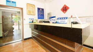 A reception area with a glass door, a counter with informational posters, and a red Chinese character sign.