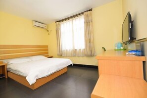 A room with a bed, a desk, a chair, a window with curtains, and a mounted TV. - Tianci Liangyuan Hotel (Beijing Tongzhou Fuheyuan) (Beijing)
