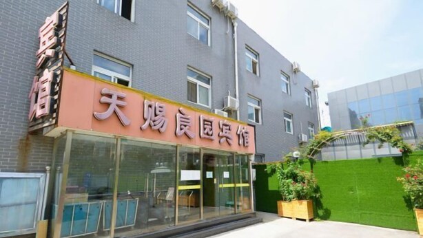 A building with a sign that reads "天厨良园宾馆" (Tianchu Laoyuan Guesthouse).