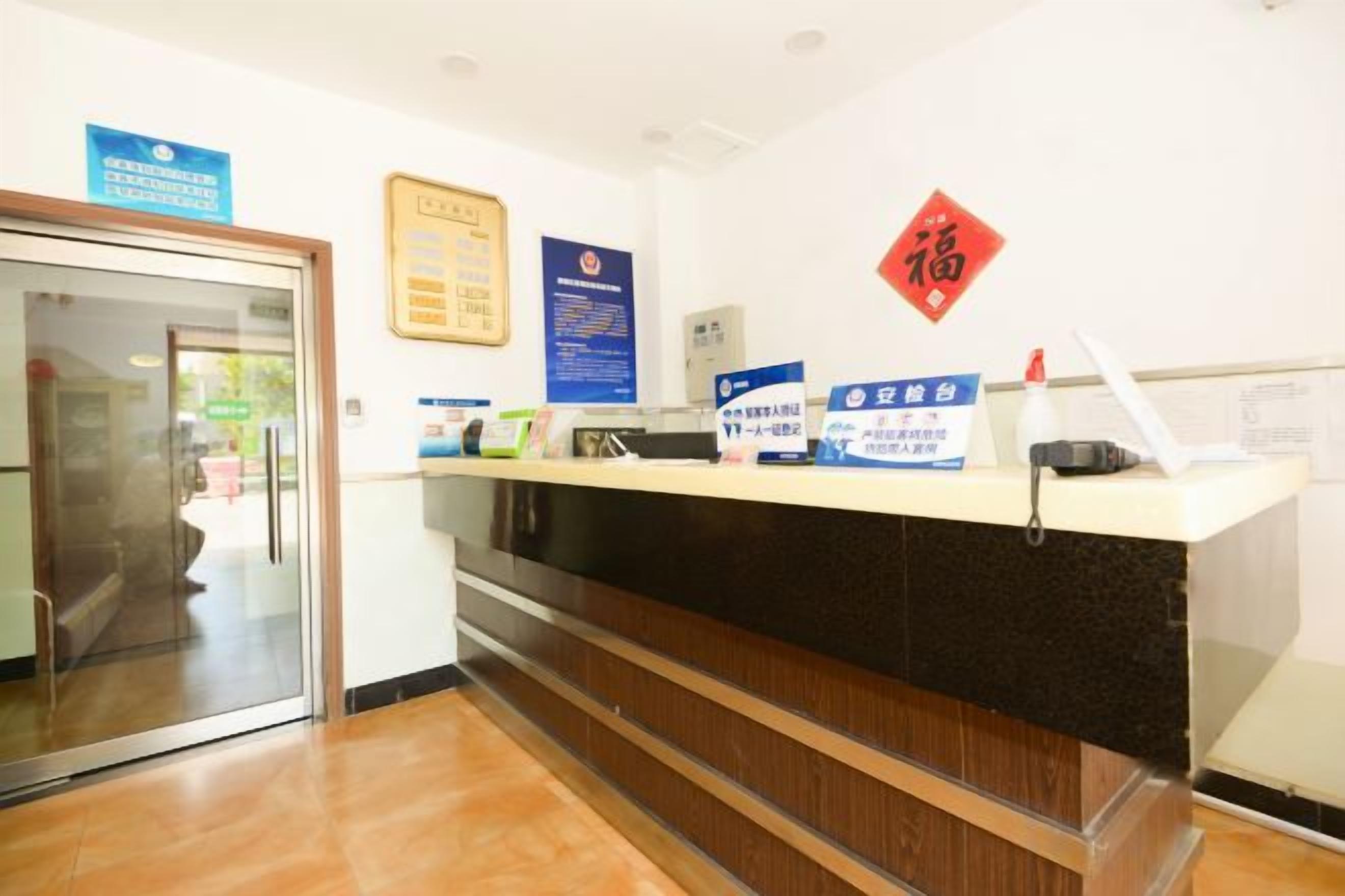 A reception desk with informational posters, a red decorative element, and a laptop.