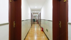 A long, narrow hallway with wooden doors on either side and a tiled floor.