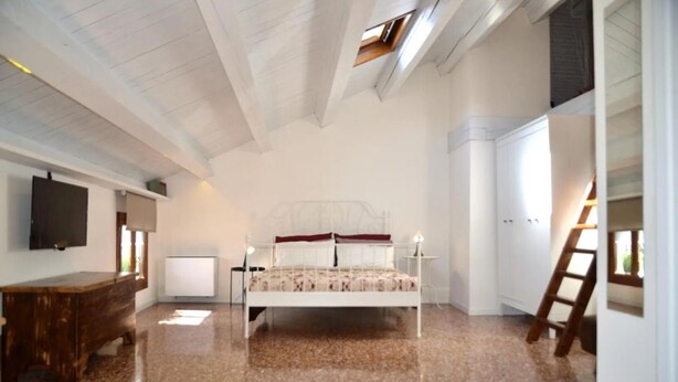 Un dormitorio con una cama, un escritorio, un televisor y una ventana.