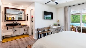 A modern hotel room with a bed, a desk, a chair, a TV, and a view of a swimming pool. - Mid-Century Modern | Pool & Spa | Mountain Views (Palm Springs)