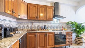 A kitchen with wooden cabinets, a built-in oven, and a tiled backsplash. - Patio Suite - Unique and Close to the Sea in El Campello (El Campello)