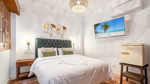 A bedroom with a bed, a nightstand, a dresser, a wall-mounted picture, and a ceiling light fixture. - Patio Suite - Unique and Close to the Sea in El Campello (El Campello)