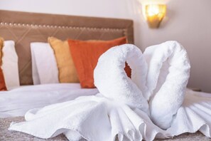Ein Bett mit weißen Handtüchern, die zu einem Herz geformt sind, einem braunen Kopfteil und einer Wandleuchte.