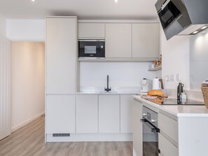 A modern kitchen with white cabinetry, a Bosch microwave, a coffee maker, and a bread loaf on the counter.