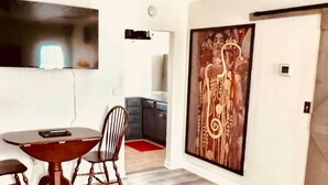 Un salon moderne comprenant un coin repas, une grande peinture abstraite et un tapis à motifs.