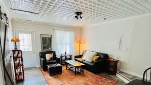 Un salon avec un plafond orné de motifs, un canapé, une table basse et un tapis.