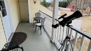 Une véranda abritée avec un télescope, deux chaises et une table.