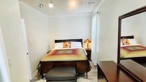 Une chambre à coucher comprenant un lit, une commode, un miroir, un tapis moelleux et un plafond doté d’un éclairage encastré.
