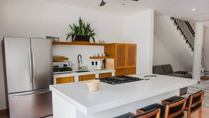 Eine moderne Küche mit einer zentralen Kochinsel, Edelstahlgeräten, Holzschränken und einer Treppe zu einer weiteren Ebene.