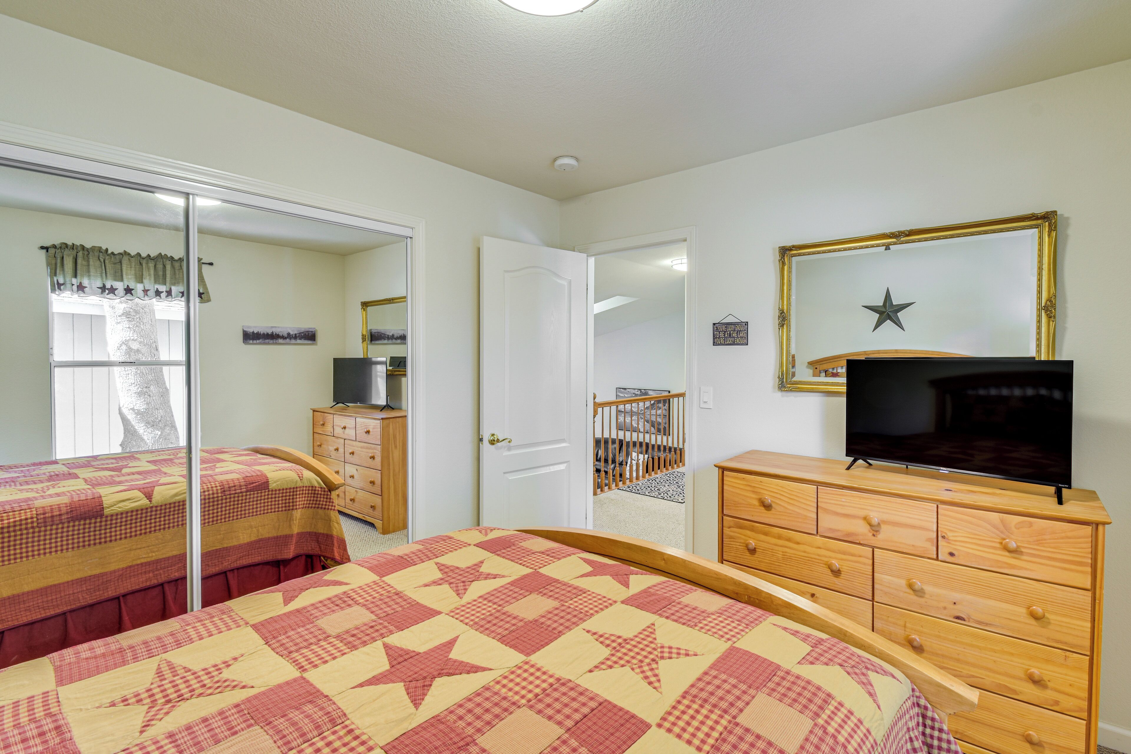 A bedroom with two beds, a dresser, a television, and a mirror.
