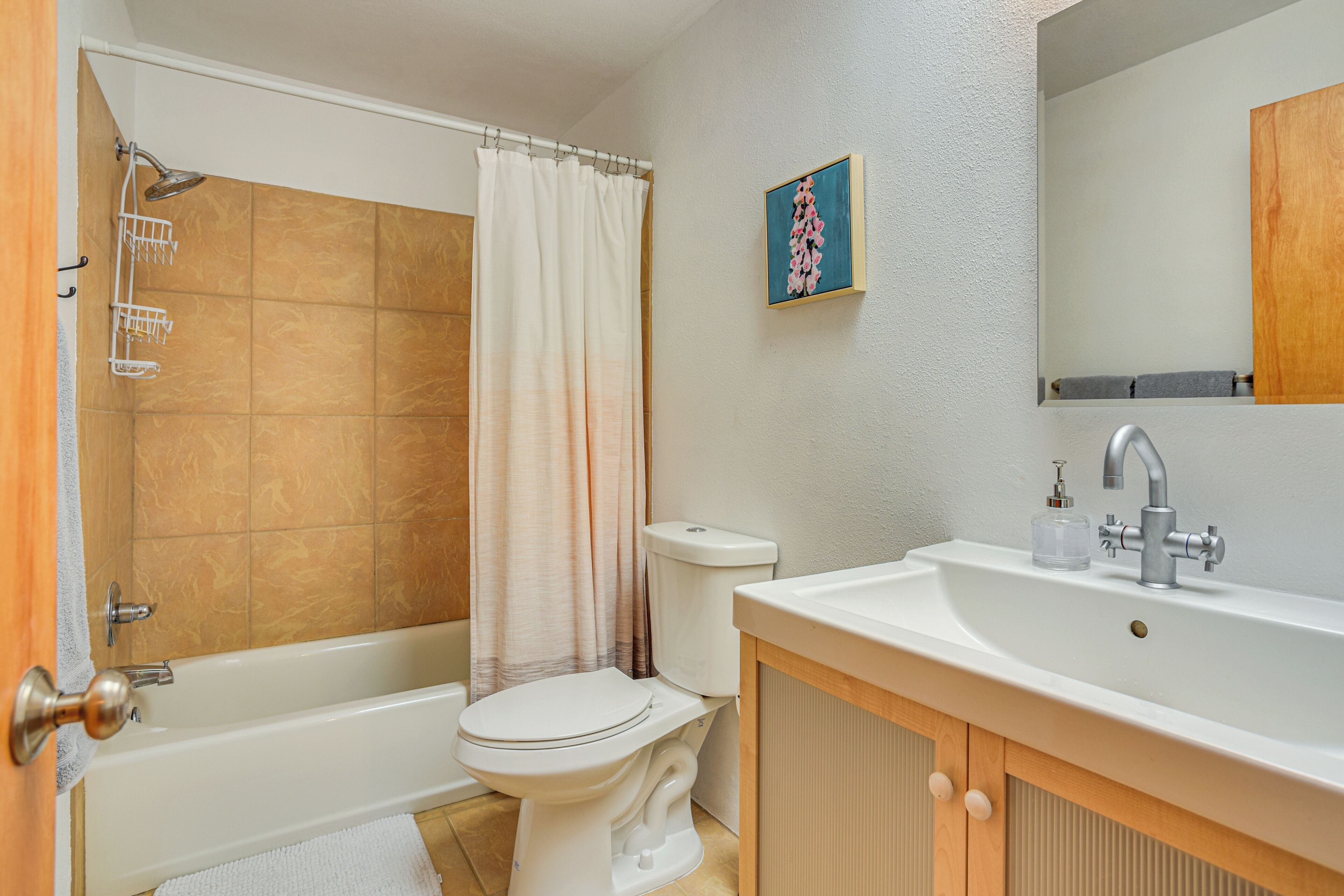 Une salle de bain équipée d’une baignoire, de toilettes, d’un lavabo et d’un rideau de douche.