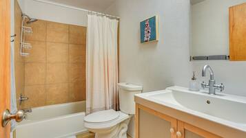 Une salle de bain équipée d’une baignoire, de toilettes, d’un lavabo et d’un rideau de douche.