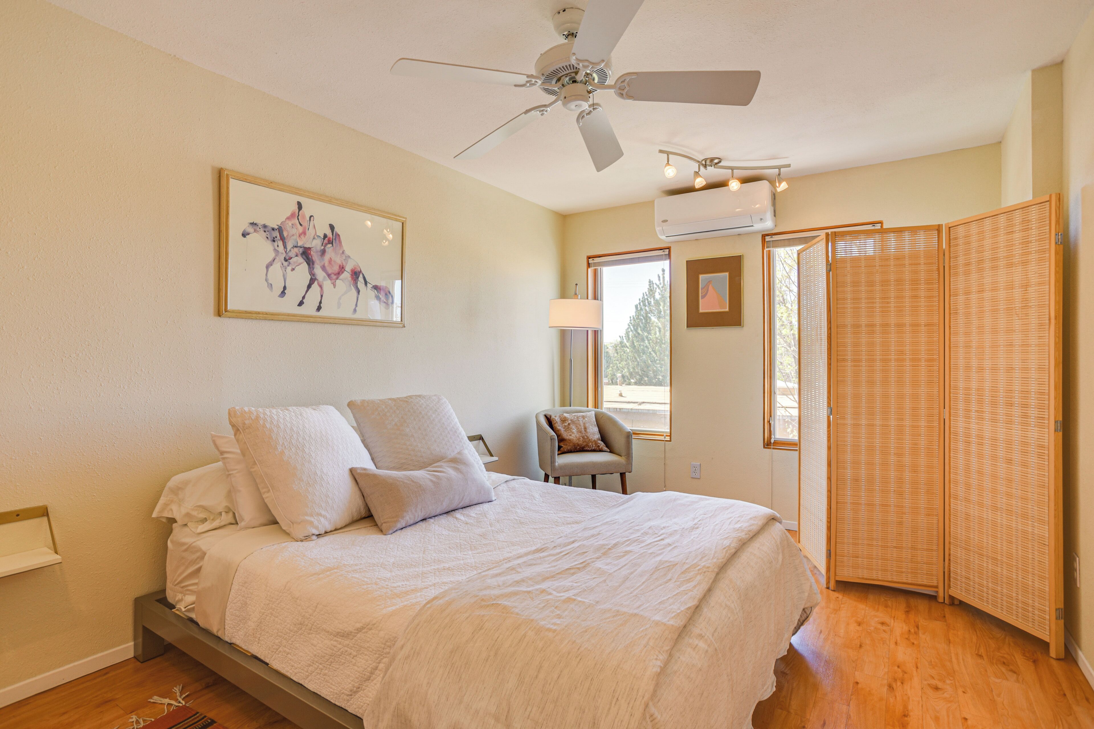 Une chambre à coucher avec un lit, une chaise, une fenêtre et un ventilateur de plafond.