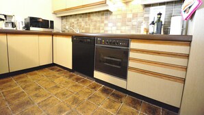A kitchen with a dishwasher, oven, microwave, and tiled backsplash. - Bright 3-bedroom Apartment With Sea View (Knokke-Heist)