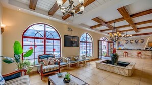 A spacious living area with large windows, a fireplace, and a kitchen in the background. - Mengzi Fengjing Boutique Hotel (Mengzi)