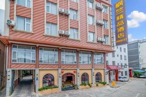 Un hotel de varios pisos con fachada roja, múltiples ventanas y una entrada visible con toldo rojo.