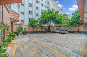 Un estacionamiento con espacios delimitados, un edificio con varias ventanas y plantas en macetas a lo largo del sendero.