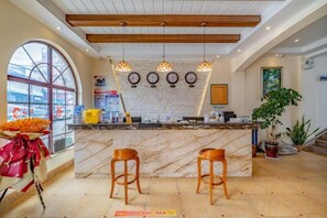 A hotel lobby with a marble reception desk, wooden ceiling beams, and a large window.