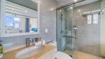 Een moderne badkamer met een douche met glazen wand, een marmeren wastafel en een toilet.