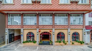Een gebouw met twee verdiepingen, een gevel in rood en beige, meerdere ramen en een centrale ingang met een rode boog.