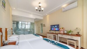 A hotel room with a large bed, a desk, a television, and a view of the city through the window. - Mengzi Fengjing Boutique Hotel (Mengzi)