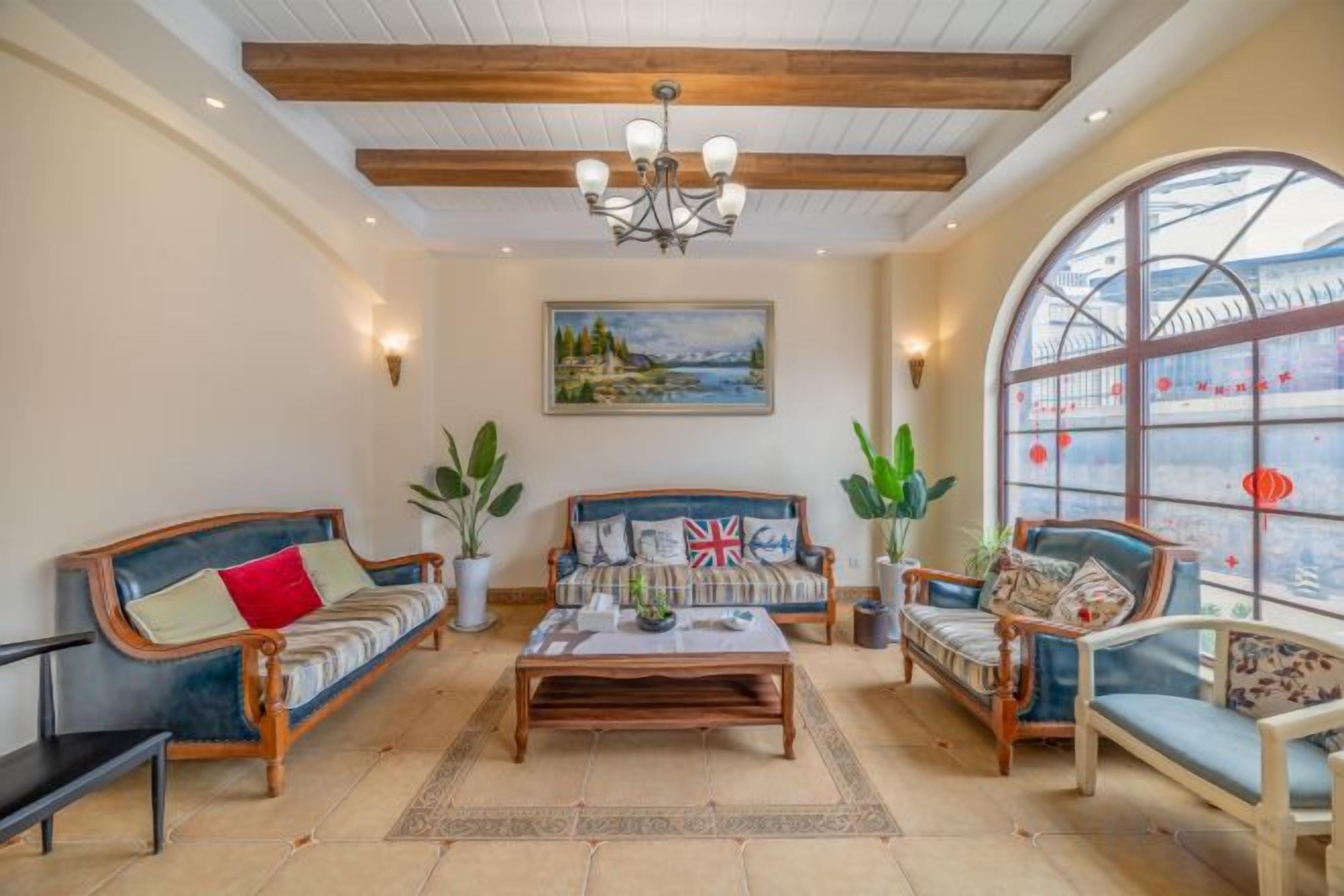 A spacious living room with a high ceiling, a central coffee table, and seating arrangements including sofas and chairs.