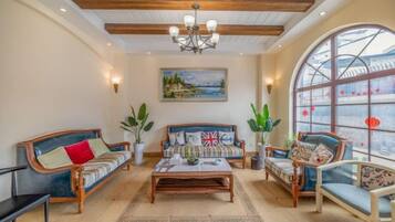 A spacious living room with a high ceiling, a central coffee table, and seating arrangements including sofas and chairs.