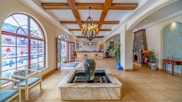 A spacious lobby with a central fountain, large arched windows, and wooden ceiling beams. - Mengzi Fengjing Boutique Hotel (Mengzi)