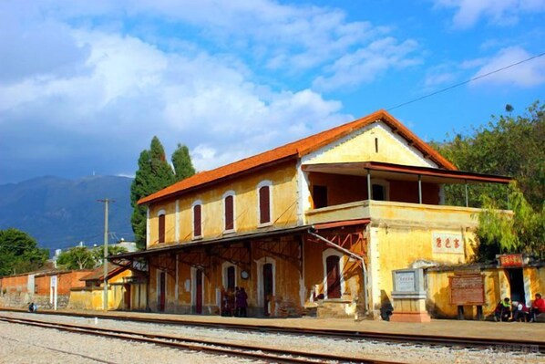A train station with a single-story building, a covered waiting area, and a platform.