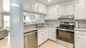 A modern kitchen with white cabinetry, a stainless steel dishwasher, a double oven, and a granite countertop. - 1 Mi to Barefoot Landing: Condo w/ Pool Access! (North Myrtle Beach)