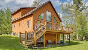 A two-story wooden house with a balcony, a staircase, and a patio area with outdoor furniture. - Pet Friendly Lake House: Waterfront w/ Boat Dock (Eagle River)