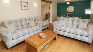 Ein Wohnzimmer mit zwei karierten Sofas, einem Holztisch und einer Wanduhr.