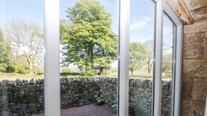 Eine Steinsäule und ein Baum sind von einem Fenster aus in einem Garten zu sehen.