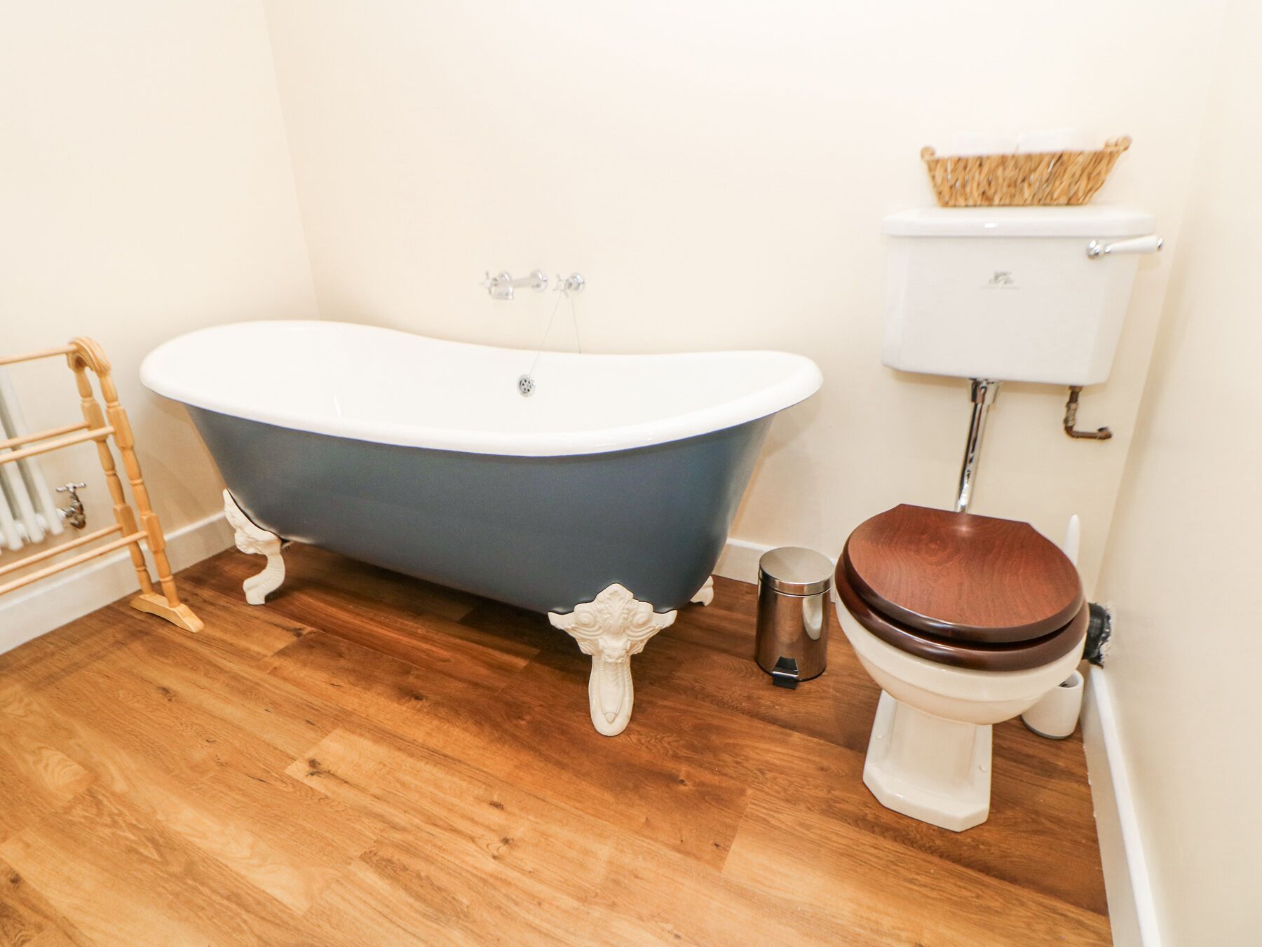 A bathroom with a freestanding bathtub, a toilet, and a metal trash bin.