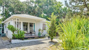 A white house with a porch, surrounded by greenery and trees. - 4 Mi to Daytona Boardwalk & Beaches: Cute Cottage (Holly Hill)
