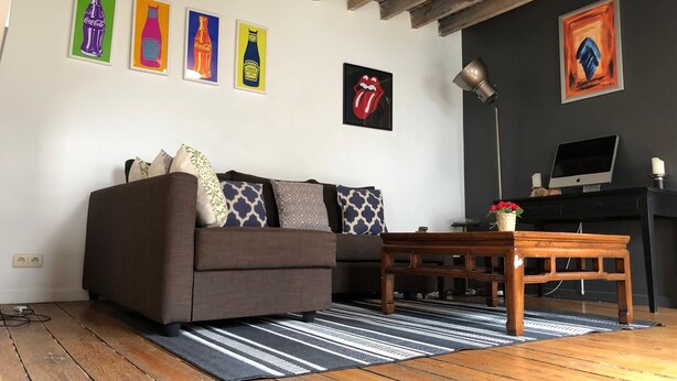 A living room with a sofa, coffee table, and artwork on the wall.