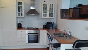 A compact kitchen with white cabinets, a gas stove, a microwave, and a sink.