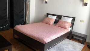 A bedroom with a bed, bedside tables, a rug, and a wardrobe.