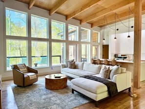 A spacious living room with a large window, a sofa, a chair, and a coffee table.