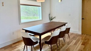 Un comedor con una mesa y sillas de madera, una lámpara colgante, una ventana con persianas y una puerta.