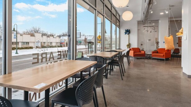 A modern indoor space with large windows, wooden tables, black chairs, and orange seating. - Cedar Tree House 319 (Traverse City)