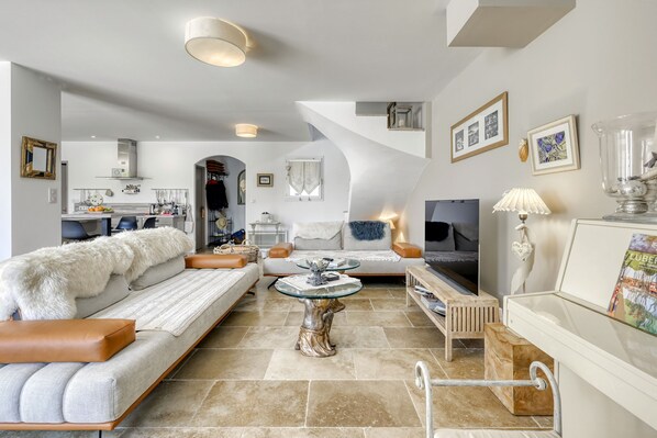 A spacious living area with a sofa, a coffee table, and a TV. There is a staircase leading to an upper level. - Villa Vittoria, 6-8 ppl. AC & Heated Pool (Villelaure)