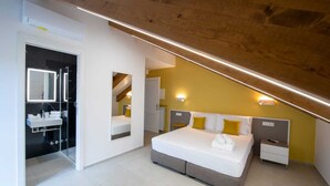 Un dormitorio moderno con una cama grande, mesitas de noche, un vestidor y un baño con cabina de ducha de vidrio.